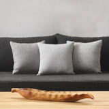 Decorative pillows on a greyish black sofa.