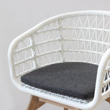 White rattan chair with a dark gray cushion on a plain background