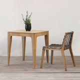 Wooden table with a plant and chair on a wooden floor against a white wall