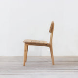 Outdoor wooden chair with rounded backrest on a wooden floor against a plain wall