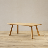 Wooden dining table on a wooden floor with a plain wall background