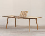 Outdoor extended dining table on a wooden floor against a plain wall