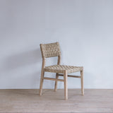 Woven chair against a plain wall on a wooden floor.