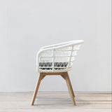 Rattan chair with wooden legs on a light wooden floor against a white wall