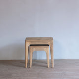 Wooden nesting table against a plain wall.