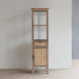 Tall wooden cabinet with rattan door and drawer against a plain wall