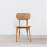 Outdoor wooden chair with rounded backrest on a wooden floor against a plain wall