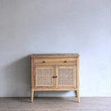 Wooden cabinet with rattan doors against a plain wall