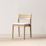 Outdoor chair with cushion on a wooden floor againts a plain wall