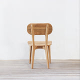 Outdoor wooden chair with rounded backrest on a wooden floor against a plain wall