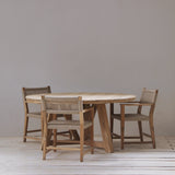 Wooden dining table with four chairs in a minimalistic room.