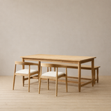 Wooden dining table with chairs on a wooden floor against a plain wall