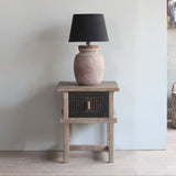 Wooden side table with a lamp against a plain wall