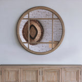 Reclaimed pine wood round mirror above a sideboard.