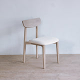 Reclaimed pine wood chair with a beige cushion on a light wooden floor and gray wall background