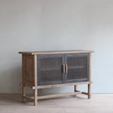 Reclaimed pine woos sideboard with rattan doors in a room with light-colored walls and wooden floor.