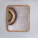 Decorative wall mirror with wooden frame and textured on a light gray background