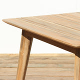 Wooden outdoor dining table with slatted top on a wooden floor with a white background