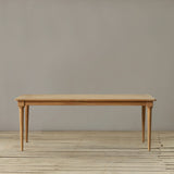 Wooden outdoor dining table on a wooden floor against a plain wall.