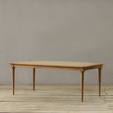 Wooden outdoor dining table on a wooden floor against a plain wall.