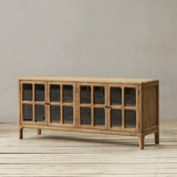 Wooden sideboard with glass doors on a wooden floor against a plain wall