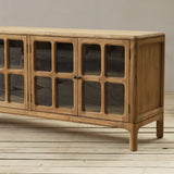 Wooden sideboard with glass panels on a wooden floor and gray wall background