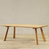 Wooden dining table on a wooden floor with a plain wall background