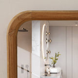 Wooden-framed mirror detail reflecting light fixtures and a sink.