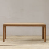 Wooden dining table on a wooden floor with a plain wall background