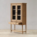 Wooden cabinet with glass doors on a wooden floor and light gray wall background