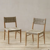 Two wooden chairs with woven pandan seats on a wooden floor against a plain wall.