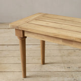 Wooden bench with a slatted top on a wooden floor with a neutral background