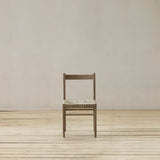 Wooden chair with woven seat on a wooden floor against a beige wall