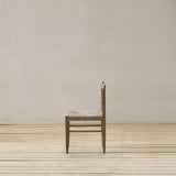 Wooden chair with woven seat on a wooden floor against a plain wall