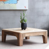 Arch Coffee Table with black potted plant on it and an abstract painting hung behind it.