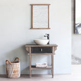 LUNAR Bathroom Cabinet with LUNAR Mirror above it. There is a woven basket next to it.