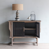 LUNAR Rattan Sideboard with one door opened. There's Pebbles Lamp and decorative items on top of it.