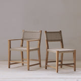 Two wooden chairs with woven seats and backrests on a light wooden floor against a plain white wall.