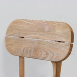 Outdoor wooden chair with rounded backrest on a wooden floor against a plain wall