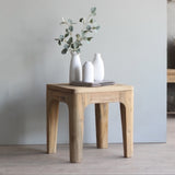 Wooden side table with decorative items in a minimalistic room.