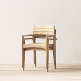 Stacked outdoor wooden armchairs on a wooden floor against a plain wall