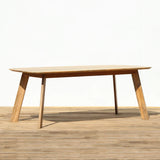 Outdoor wooden dining table on a wooden floor against a plain wall