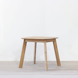 Outdoor wooden square dining table on a wooden floor against a plain wall