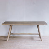 Reclaimed pine wood dining table against a plain wall with a light floor.