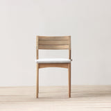 Outdoor chair with cushion on a wooden floor against a plain wall