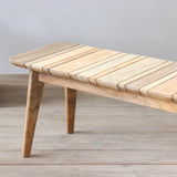 Outdoor wooden bench with slatted top on a wooden floor.