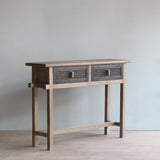 Console table with storage drawers against a light gray wall.