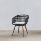Rattan chair with wooden legs on a light wooden floor and white wall background