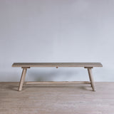 Reclaimed pine wood bench against a plain wall in a minimalistic room