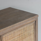 Wooden sideboard with rattan doors against a plain wall